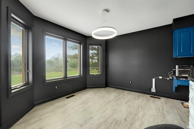 unfurnished dining area featuring light wood finished floors and baseboards