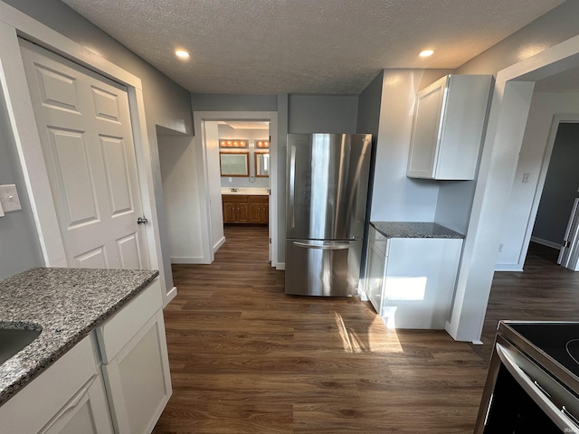 807 Walnut St, Oolitic, IN 47451 - kitchen with appliances with stainless steel finishes, a textured ceiling, white cabinetry, dark wood-style floors, and dark stone countertops