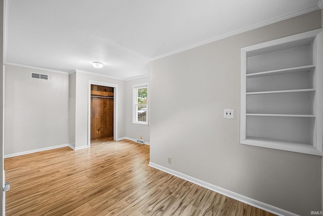 unfurnished room with baseboards, ornamental molding, wood finished floors, and built in shelves