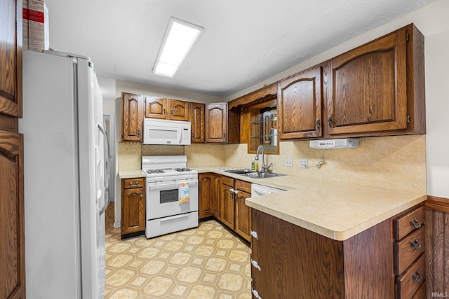 kitchen featuring white appliances, a sink, light countertops, and backsplash
