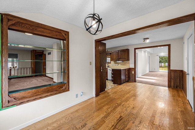 unfurnished dining area with light wood-style floors, a textured ceiling, and baseboards