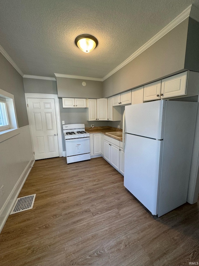 kitchen featuring white appliances, a textured ceiling, white cabinetry, dark wood-style flooring, and ornamental molding