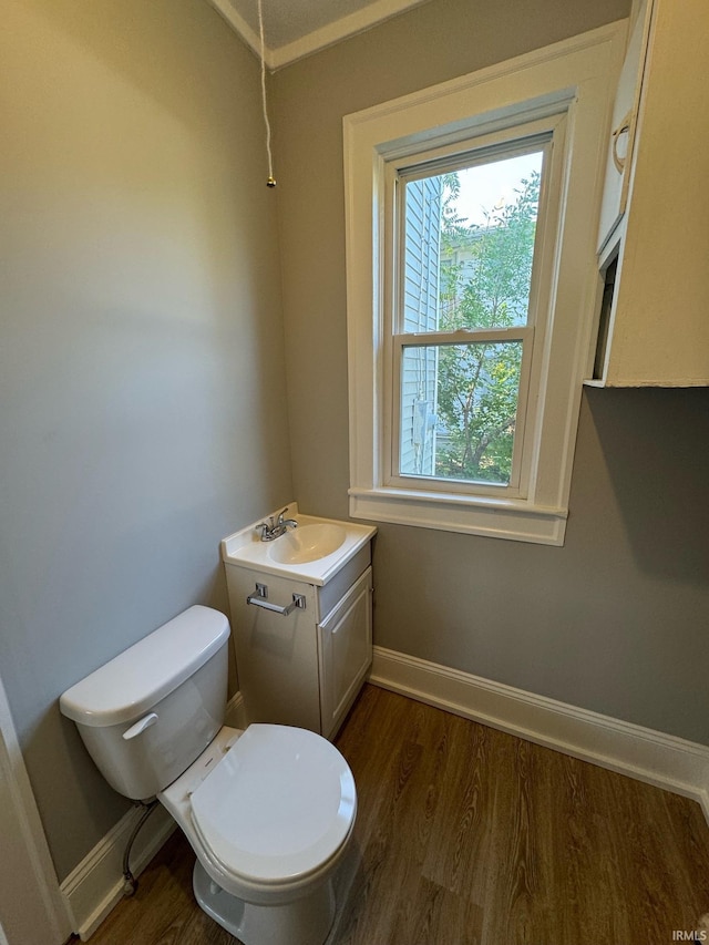 bathroom featuring wood finished floors, toilet, baseboards, vanity, and crown molding