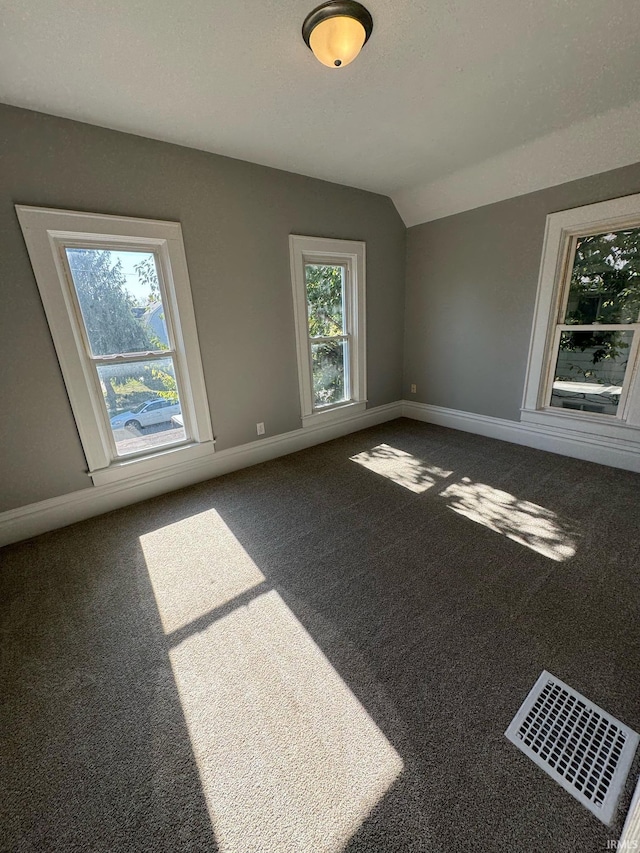 carpeted spare room featuring baseboards and lofted ceiling