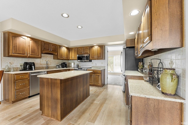kitchen with appliances with stainless steel finishes, light wood-style floors, brown cabinetry, tasteful backsplash, and recessed lighting