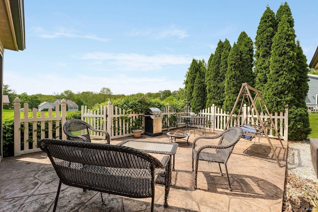 view of patio / terrace with a fire pit, grilling area, and fence