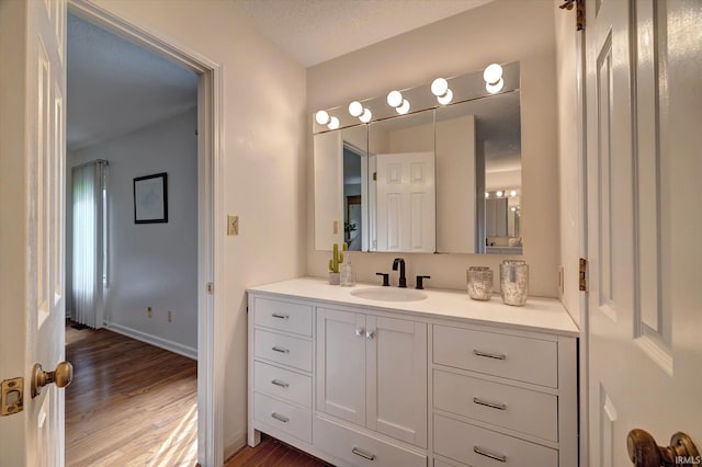 bathroom featuring wood finished floors, vanity, and baseboards