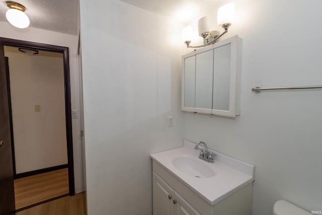 bathroom featuring vanity, wood finished floors, and toilet