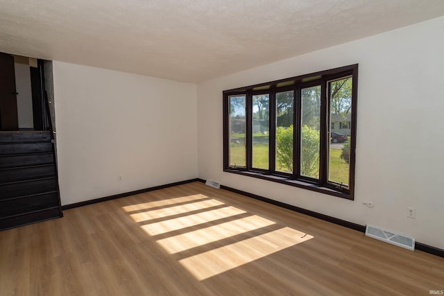 spare room featuring baseboards, wood finished floors, and stairs