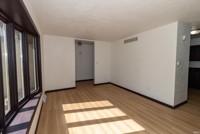 empty room with wood finished floors, baseboards, and a textured ceiling
