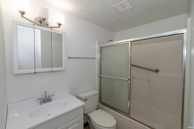 bathroom with vanity, toilet, combined bath / shower with glass door, and a textured ceiling