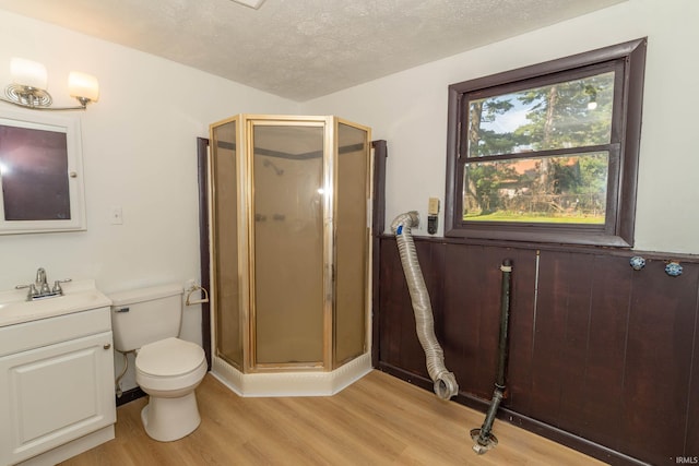 bathroom featuring wood finished floors, a shower stall, vanity, a textured ceiling, and toilet