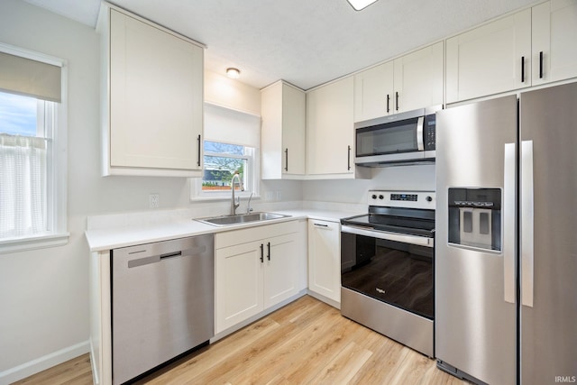 1425 Adams St, Lafayette, IN 47905 - kitchen with stainless steel appliances, a sink, light wood-style floors, light countertops, and white cabinetry