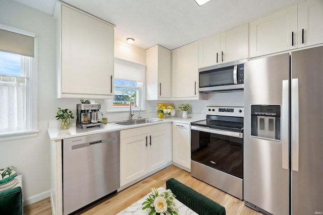 1425 Adams St, Lafayette, IN 47905 - kitchen featuring appliances with stainless steel finishes, a sink, light countertops, light wood-style flooring, and white cabinetry