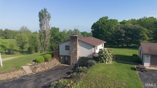 view of property exterior featuring a chimney, an outbuilding, a yard, and stone siding