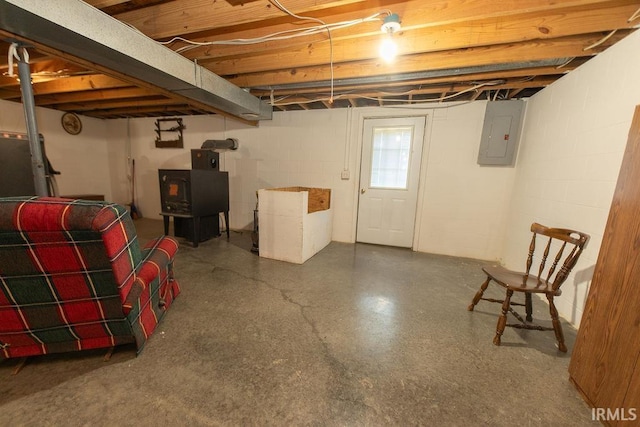 basement featuring electric panel and a wood stove