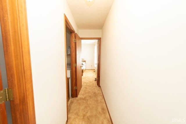hall featuring light carpet and a textured ceiling