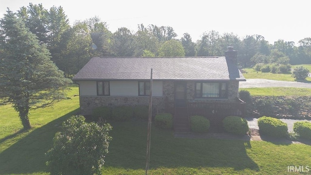 view of front of house featuring a front yard, a chimney, and stone siding
