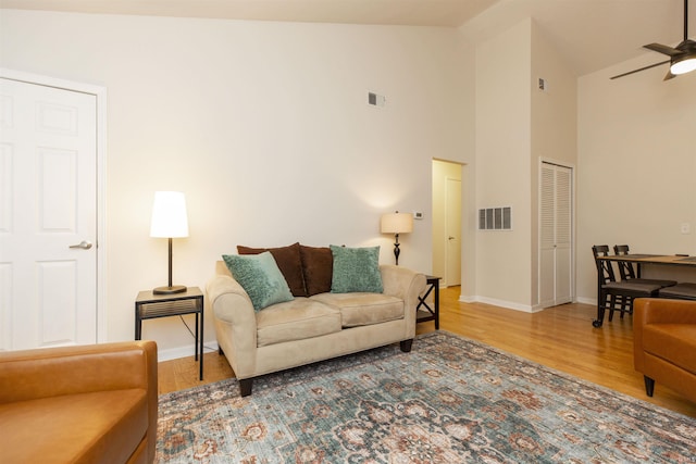 living area with wood finished floors, baseboards, high vaulted ceiling, and ceiling fan