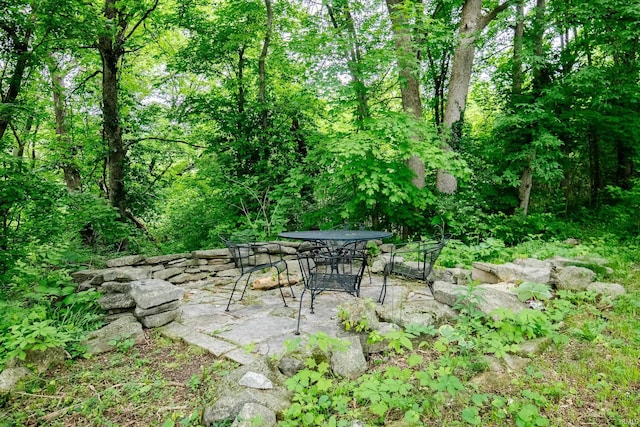 view of patio with outdoor dining space and a forest view