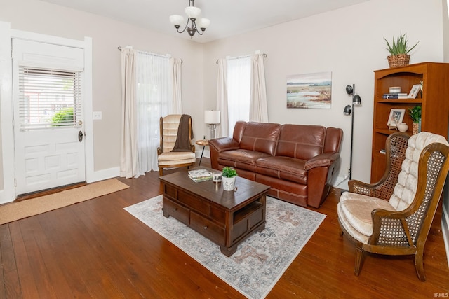 living area with dark wood-style flooring, a chandelier, and baseboards