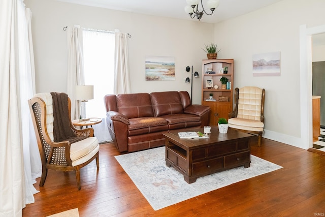 living area featuring hardwood / wood-style flooring, a chandelier, and baseboards