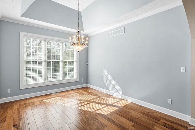 spare room featuring a chandelier, baseboards, wood finished floors, and ornamental molding