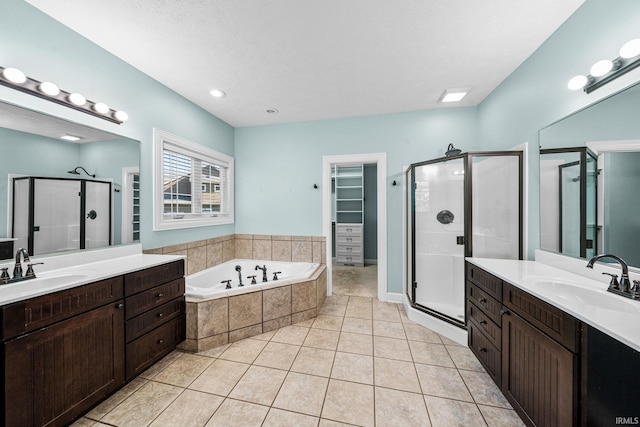 full bathroom featuring a shower stall, tile patterned flooring, a bath, and two vanities