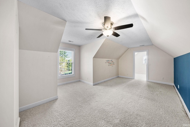bonus room with vaulted ceiling, carpet floors, baseboards, a textured ceiling, and a ceiling fan