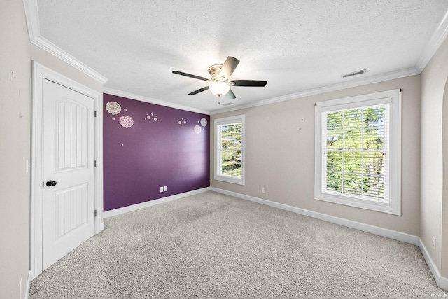 spare room featuring ceiling fan, carpet flooring, a textured ceiling, baseboards, and ornamental molding