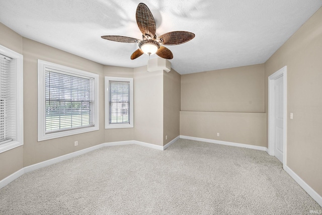 carpeted empty room with a ceiling fan, baseboards, and a textured ceiling