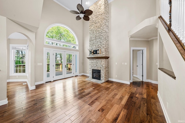 unfurnished living room with high vaulted ceiling, a fireplace, a ceiling fan, healthy amount of natural light, and baseboards
