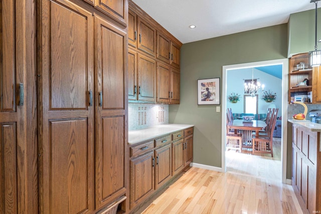 kitchen featuring brown cabinetry, light wood-type flooring, backsplash, light countertops, and recessed lighting