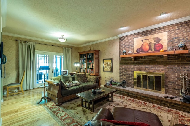 living area featuring wood finished floors, a textured ceiling, crown molding, french doors, and a fireplace