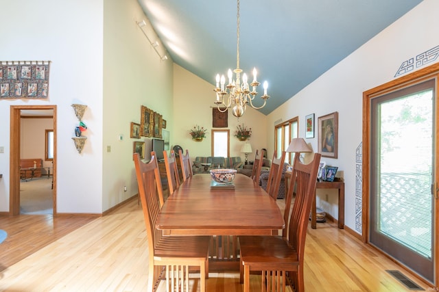 dining room with a chandelier, light wood-style flooring, high vaulted ceiling, baseboards, and rail lighting