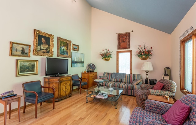 living area featuring healthy amount of natural light, wood finished floors, and high vaulted ceiling