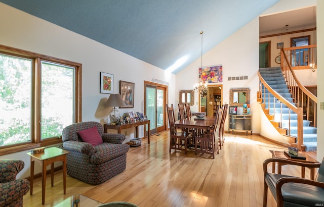 dining space with stairway, a chandelier, hardwood / wood-style floors, and high vaulted ceiling