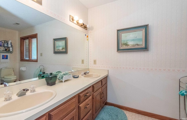 bathroom with double vanity and toilet