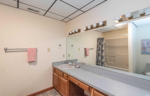 full bath featuring vanity, a paneled ceiling, baseboards, and toilet