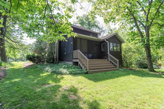 rear view of property featuring a sunroom, a lawn, and stairs