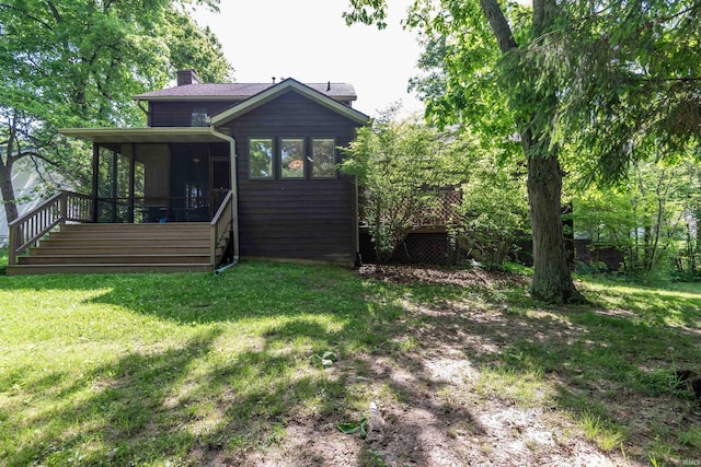 back of property featuring a sunroom, a chimney, a lawn, and stairs