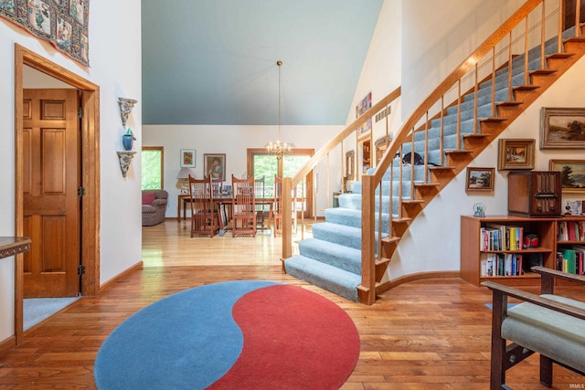 stairway featuring a towering ceiling, a chandelier, hardwood / wood-style flooring, and baseboards