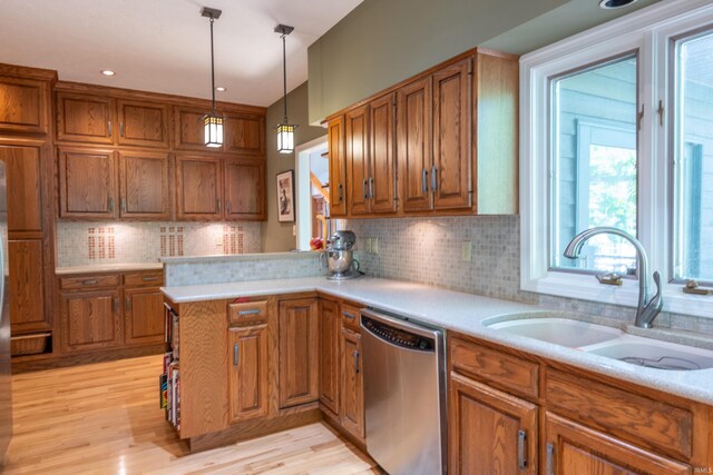 kitchen featuring dishwasher, brown cabinetry, a sink, and light countertops