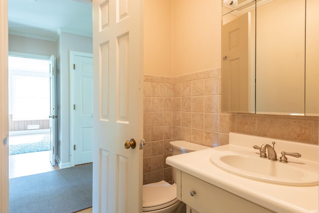 half bath with toilet, ornamental molding, tile walls, and vanity