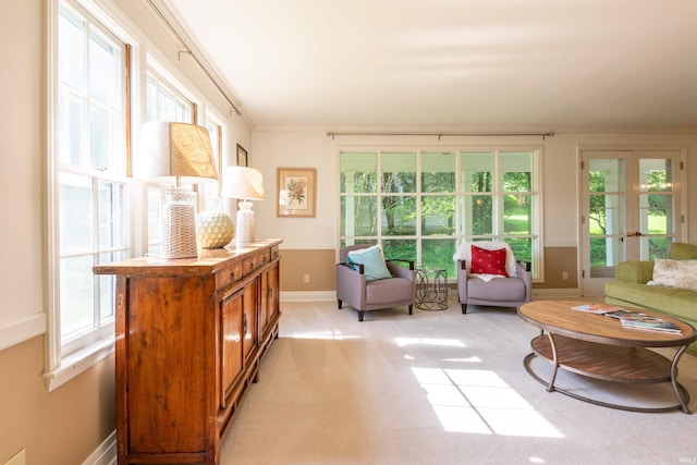 sitting room featuring healthy amount of natural light, french doors, light colored carpet, baseboards, and ornamental molding