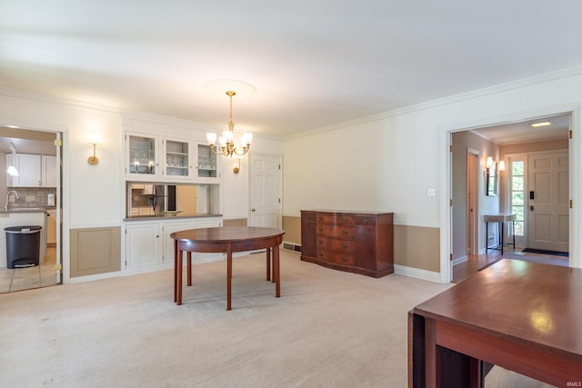 dining area with a chandelier, ornamental molding, and light colored carpet