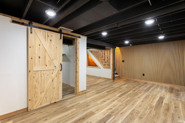 finished basement featuring a barn door, stairs, and wood finished floors
