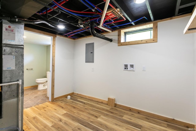 below grade area with electric panel, wood finished floors, and baseboards
