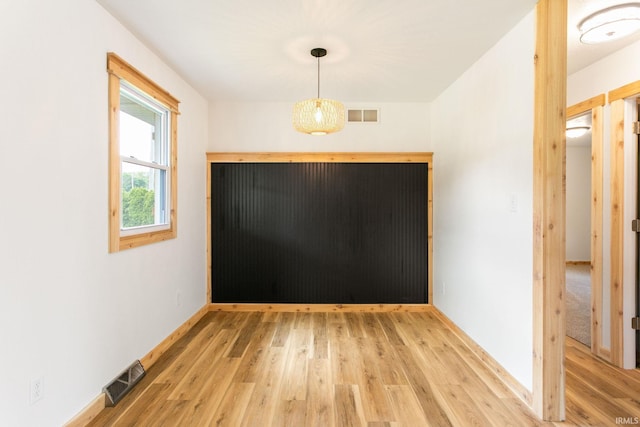 unfurnished dining area featuring light wood-type flooring and baseboards