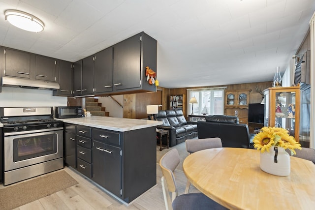 47 Ems W29B Ln, North Webster, IN 46555 - kitchen with gas stove, under cabinet range hood, black microwave, light wood-style floors, and wood walls